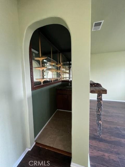 hall featuring visible vents, dark wood finished floors, and baseboards