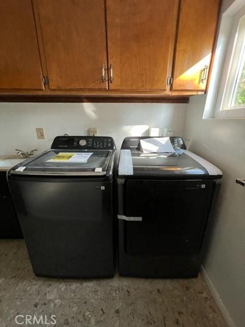 laundry room featuring washer and clothes dryer and cabinets