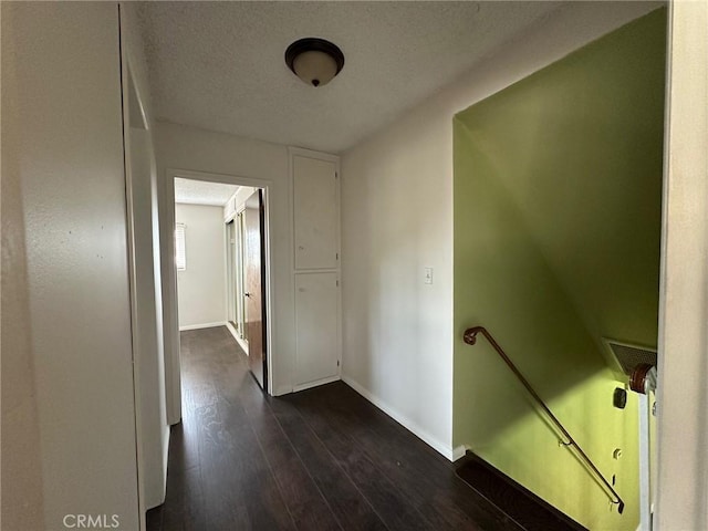 hallway featuring a textured ceiling and dark hardwood / wood-style floors