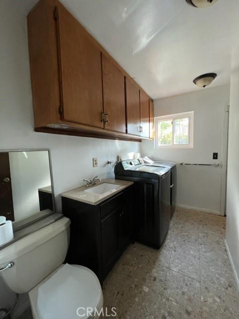 washroom with laundry area, baseboards, washer and clothes dryer, and a sink