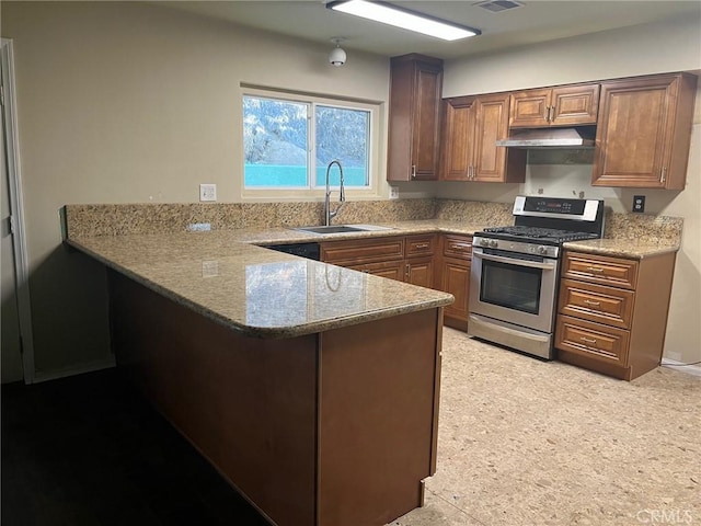 kitchen with stainless steel gas range oven, a peninsula, light stone countertops, under cabinet range hood, and a sink