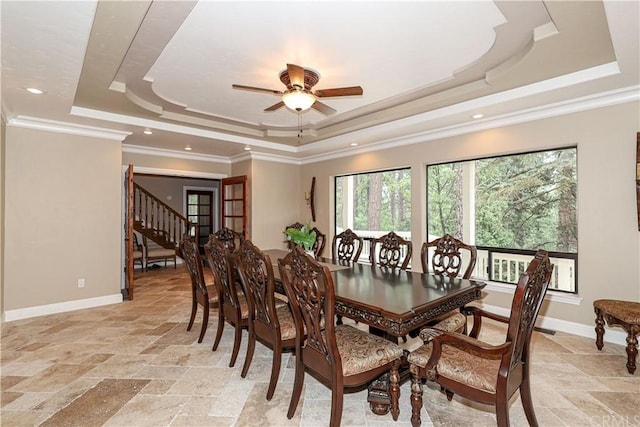 tiled dining space with a tray ceiling, ceiling fan, and ornamental molding