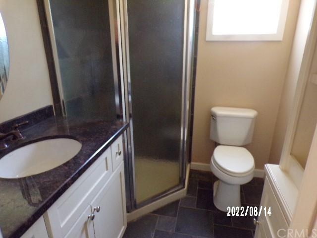 13425 Jensen Rd, Clearlake Oaks, CA 95423 - bathroom featuring toilet, tile flooring, an enclosed shower, and vanity with extensive cabinet space