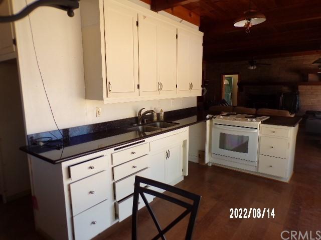 13425 Jensen Rd, Clearlake Oaks, CA 95423 - kitchen featuring dark hardwood / wood-style floors, ceiling fan, sink, white range with gas stovetop, and white cabinetry