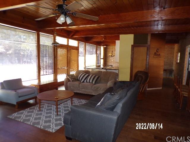 13425 Jensen Rd, Clearlake Oaks, CA 95423 - living room with brick wall, dark hardwood / wood-style floors, ceiling fan, beamed ceiling, and wooden ceiling