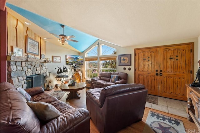 living room featuring lofted ceiling, light tile floors, ceiling fan, and a fireplace