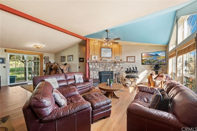 living room with a stone fireplace, light hardwood / wood-style floors, ceiling fan, and vaulted ceiling