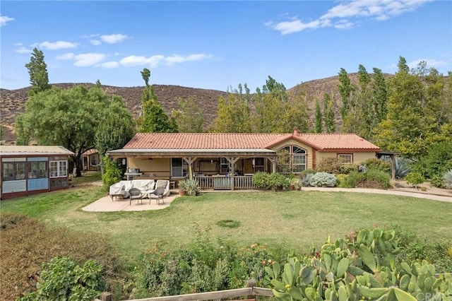 view of front of house featuring a mountain view, a front lawn, and a patio