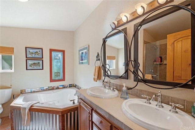 bathroom with dual vanity, a tile shower, and plenty of natural light