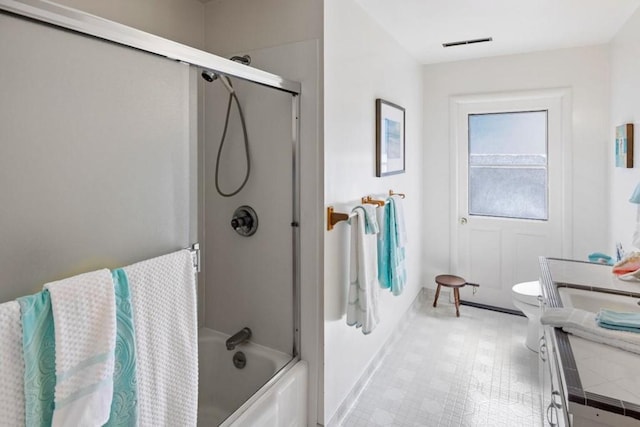 bathroom with enclosed tub / shower combo, toilet, and tile floors