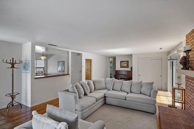 living room featuring brick wall, light hardwood / wood-style floors, and a fireplace