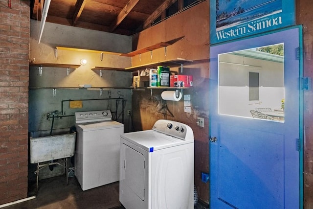 clothes washing area featuring brick wall, washer and dryer, and sink