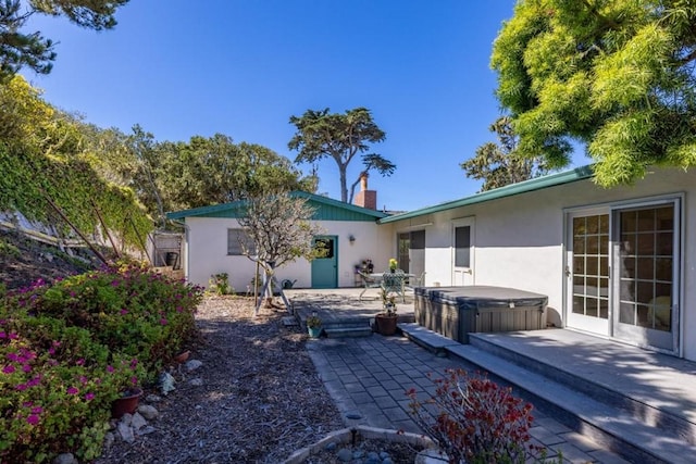 rear view of house featuring a hot tub and a patio area