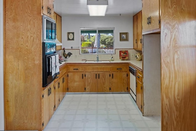 kitchen featuring backsplash, oven, white dishwasher, and sink