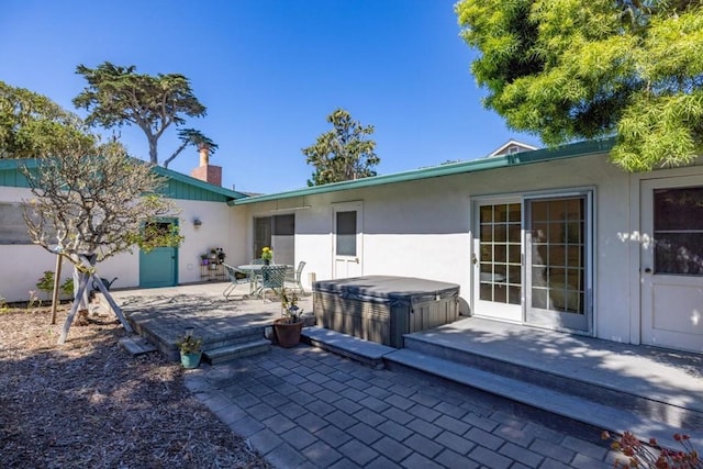 back of house featuring a wooden deck, a hot tub, and a patio area