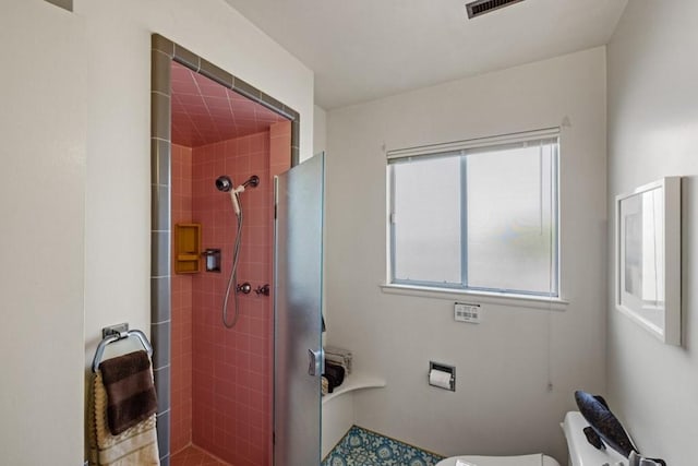 bathroom featuring toilet and a tile shower