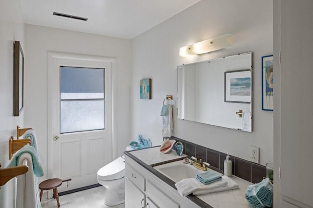 bathroom with tile floors, vanity with extensive cabinet space, and toilet