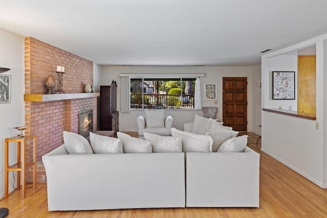 living room with brick wall, light hardwood / wood-style flooring, and a fireplace