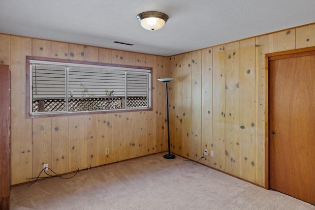 spare room featuring light carpet and wooden walls