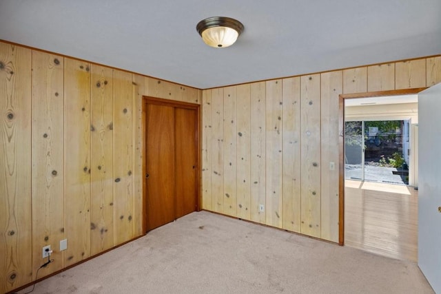 unfurnished room featuring light carpet and wood walls