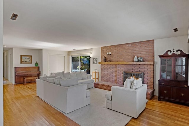 living room featuring a fireplace, brick wall, and light wood-type flooring