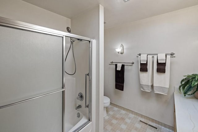 bathroom with toilet, bath / shower combo with glass door, and tile flooring