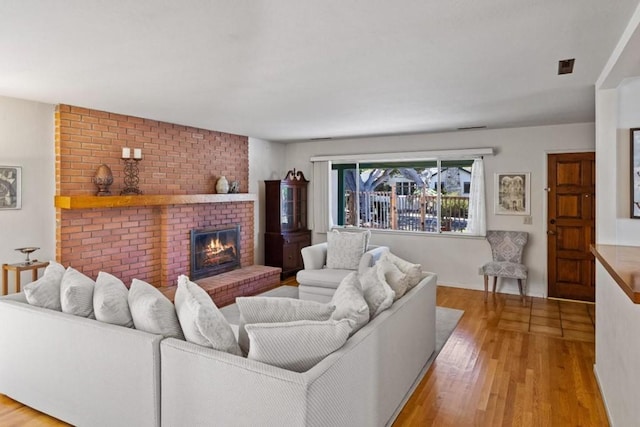 living room with brick wall, light hardwood / wood-style floors, and a fireplace