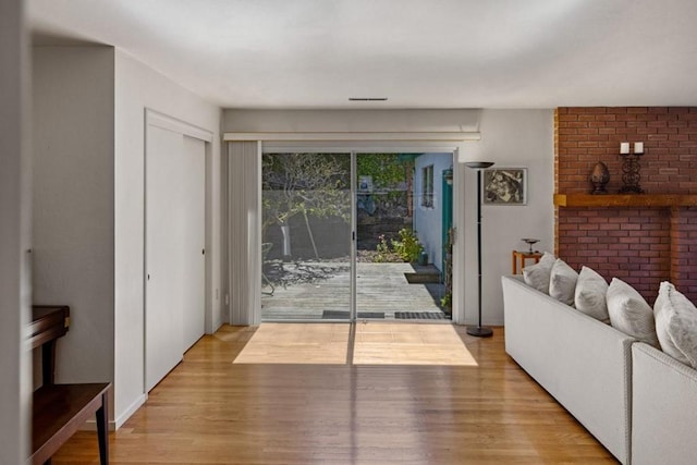 living room featuring brick wall and light hardwood / wood-style flooring