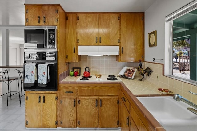 kitchen with light tile floors, black appliances, backsplash, tile countertops, and sink