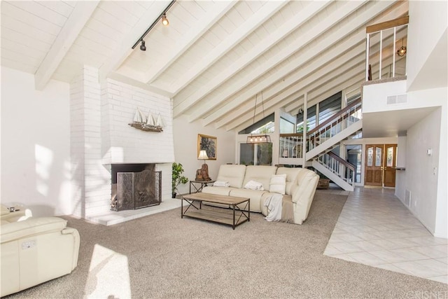 tiled living room with brick wall, a brick fireplace, rail lighting, high vaulted ceiling, and beam ceiling