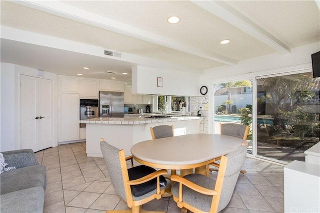 tiled dining space featuring beam ceiling