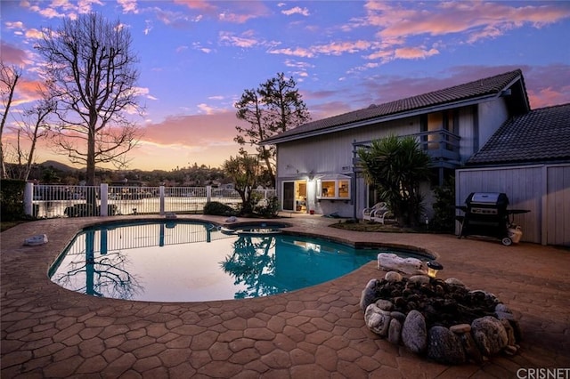 pool at dusk featuring area for grilling and a patio area