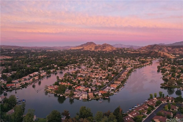 aerial view at dusk featuring a water and mountain view