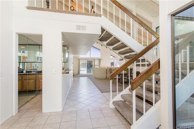 staircase featuring high vaulted ceiling and light tile floors