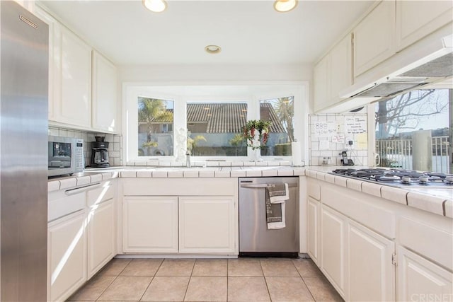 kitchen featuring white cabinetry, tasteful backsplash, a healthy amount of sunlight, and appliances with stainless steel finishes