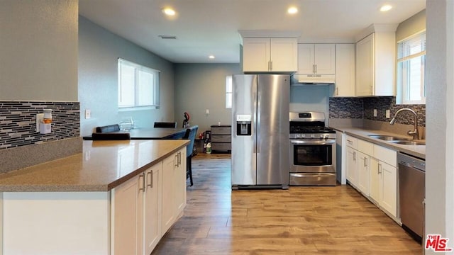 kitchen with white cabinets, stainless steel appliances, light wood-type flooring, and sink