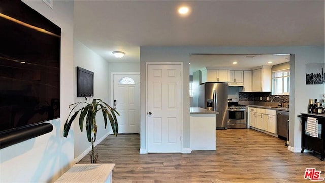 kitchen featuring white cabinetry, light hardwood / wood-style flooring, tasteful backsplash, and stainless steel appliances