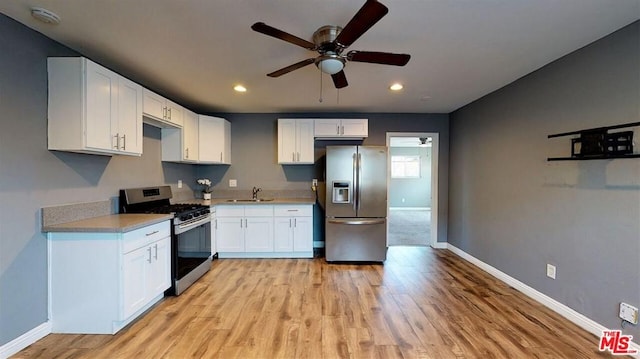 kitchen featuring stainless steel appliances, ceiling fan, white cabinetry, and light hardwood / wood-style flooring