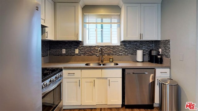 kitchen with hardwood / wood-style floors, stainless steel appliances, white cabinets, and sink