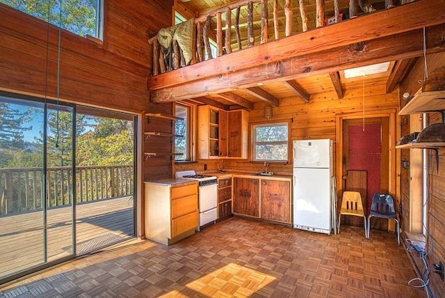 kitchen featuring white appliances, wooden walls, sink, dark parquet flooring, and a high ceiling