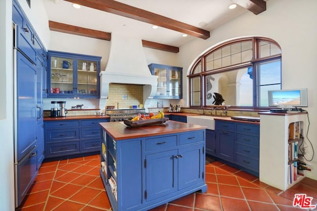 kitchen with premium range hood, blue cabinetry, a kitchen island, and plenty of natural light