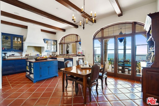 dining area with dark tile flooring, a healthy amount of sunlight, a chandelier, and beamed ceiling