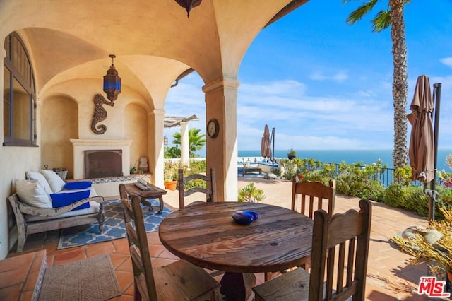 view of patio / terrace with exterior fireplace and a water view