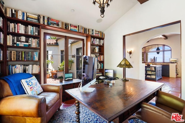 home office with lofted ceiling, a notable chandelier, and dark tile flooring