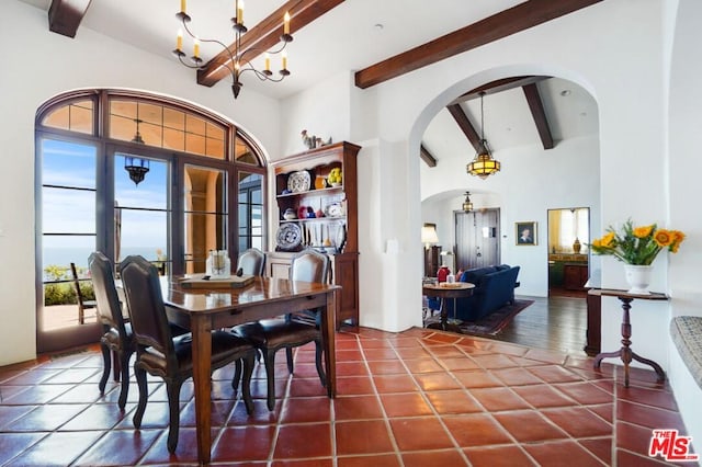 dining space featuring dark tile flooring, vaulted ceiling with beams, and an inviting chandelier