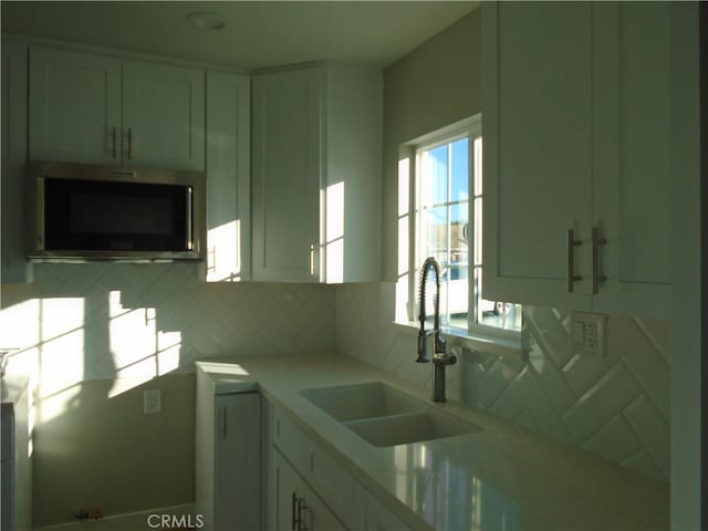 kitchen featuring white cabinets, backsplash, and sink