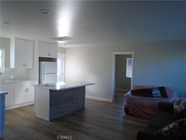 kitchen with dark hardwood / wood-style flooring, white cabinetry, white refrigerator, and a kitchen island