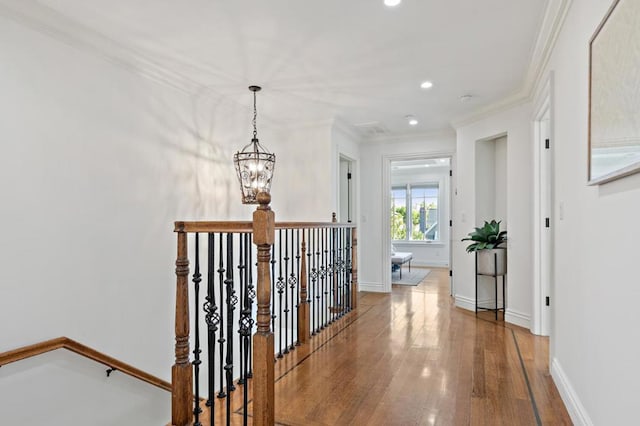 corridor featuring a notable chandelier, hardwood / wood-style floors, and crown molding