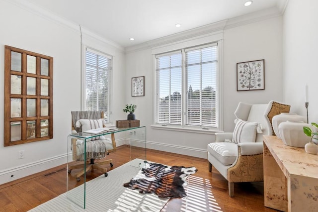 sitting room with wood-type flooring, crown molding, and a wealth of natural light