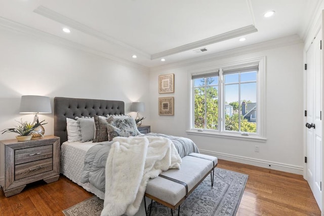 bedroom with crown molding, a tray ceiling, and dark hardwood / wood-style floors